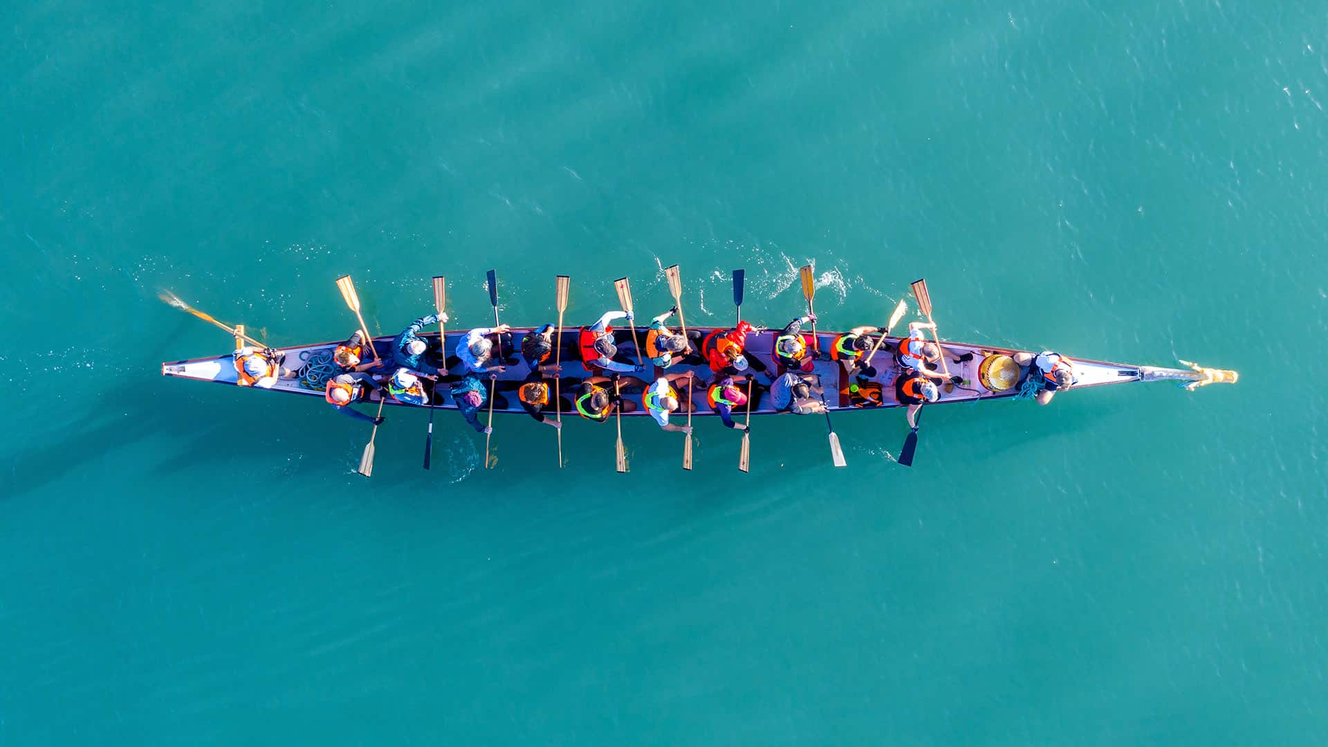 Dragon Boat team rowing to the pace of an onboard Drummer, Aeria